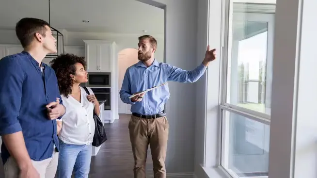 Why Wont my house sell in Las Vegas photo A real estate professional showing a couple a house, illustrating the challenges homeowners face when asking Why their house sell fast in Las Vegas