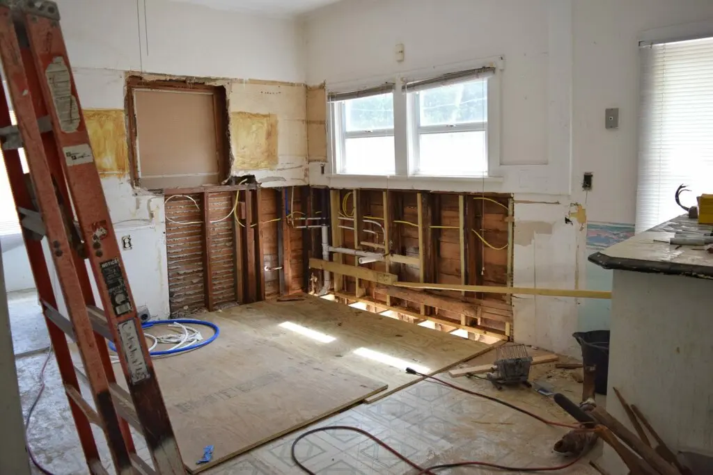 selling my house as is in nevada An unfinished kitchen under renovation, with exposed walls, wiring, and construction tools scattered on the floor, illustrating a home in need of repairs often sold 'as-is' without the seller making improvements.