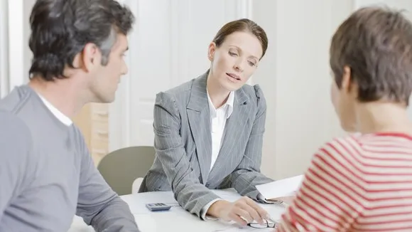 Advisor giving clients tax savings plans when selling their inherited home A financial advisor discussing tax-saving strategies with a couple selling their inherited home.