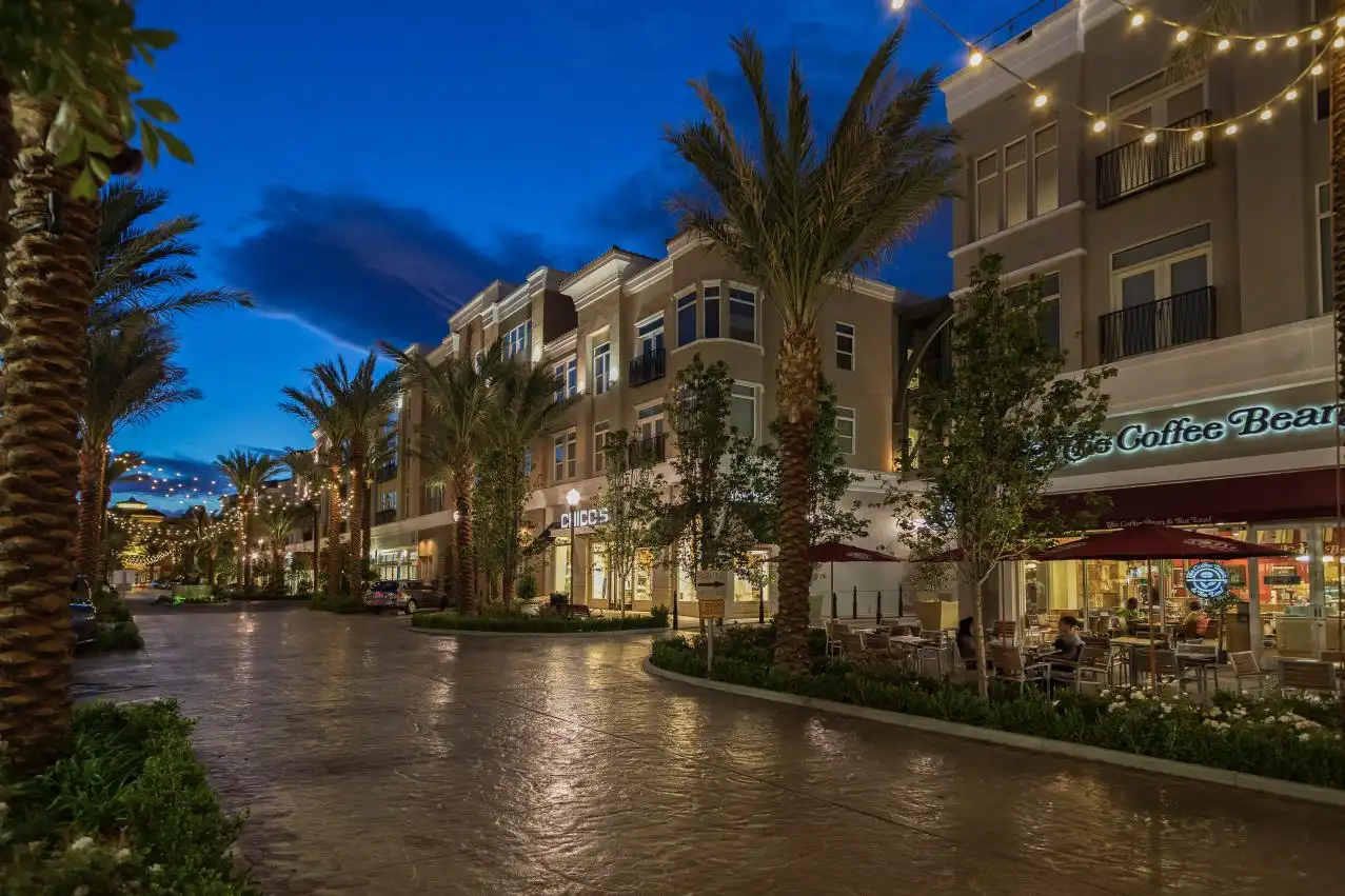 Green Valley Ranch District Evening view of The District at Green Valley Ranch in Henderson, Nevada, featuring palm-lined streets, outdoor dining at The Coffee Bean, and upscale shopping—showcasing the vibrant lifestyle of this popular Henderson neighborhood