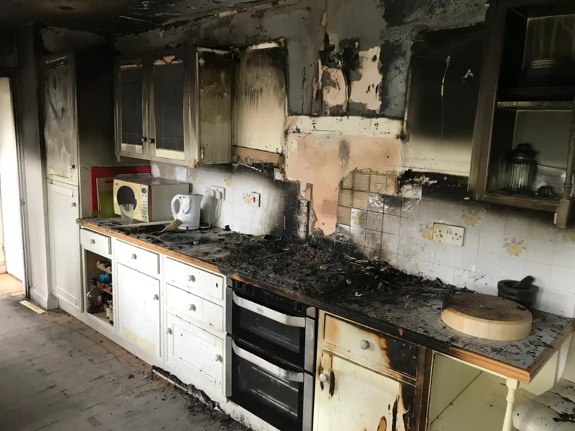 picture of a fire damaged property in north las vegas. The picture shows scorch marks from the fire of a kitchen. White cabinets charred black and appliances scorched.
