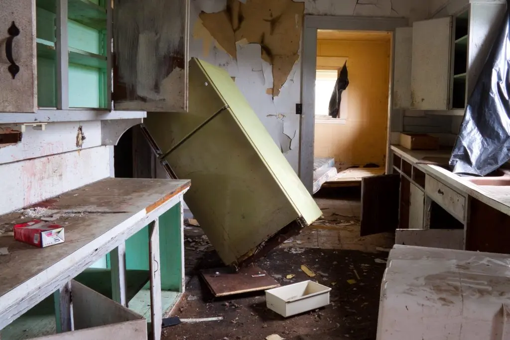 Selling a House with problem tenants Severely damaged and cluttered kitchen in a neglected home, illustrating the challenges of selling a house with problematic tenants.