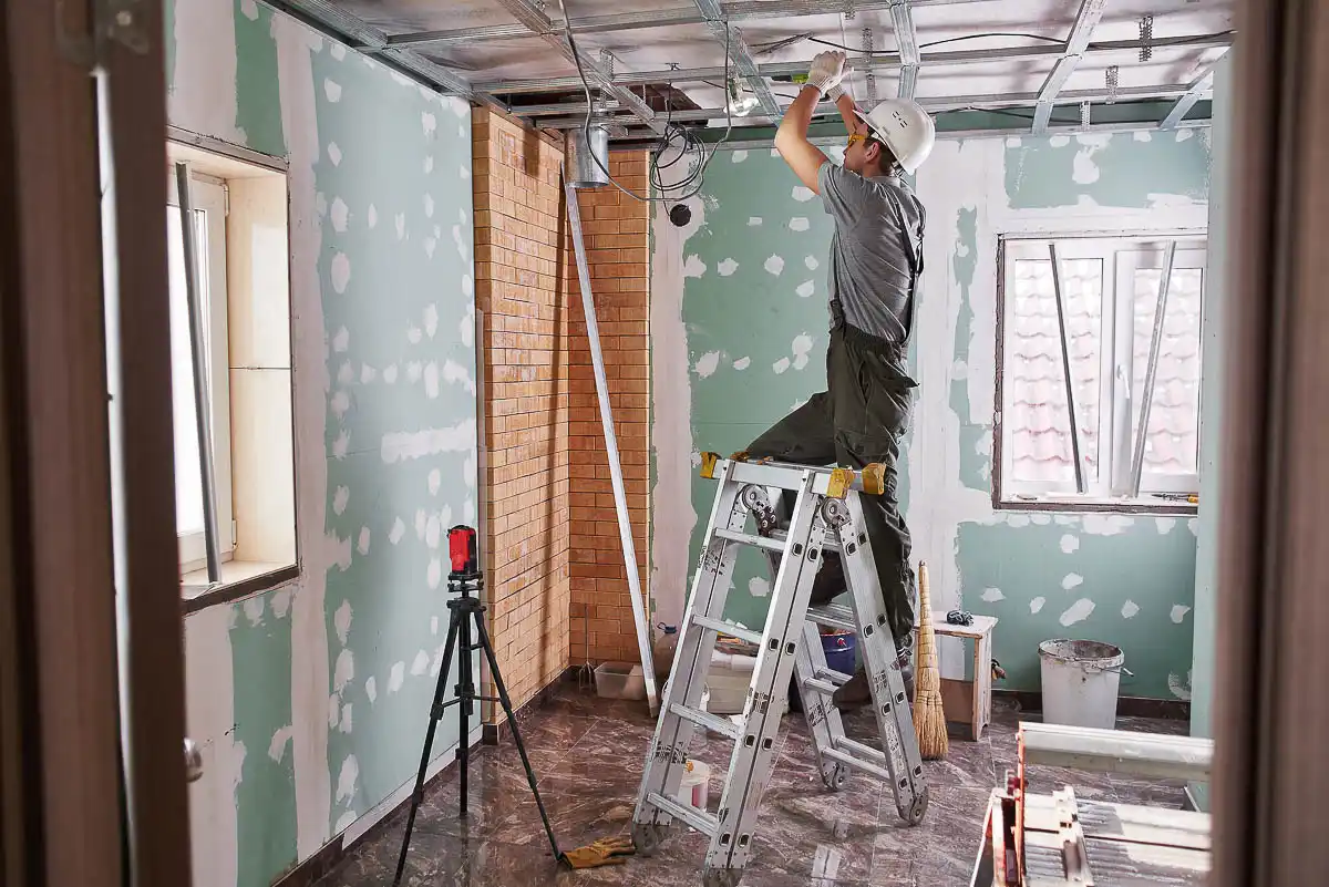 Trying to Sell a House that Needs Major Repairs in Las Vegas Construction worker repairing ceiling in a partially renovated room, showing the challenges of selling a house that needs major repairs, one of the primary reasons to sell your house to an investor.