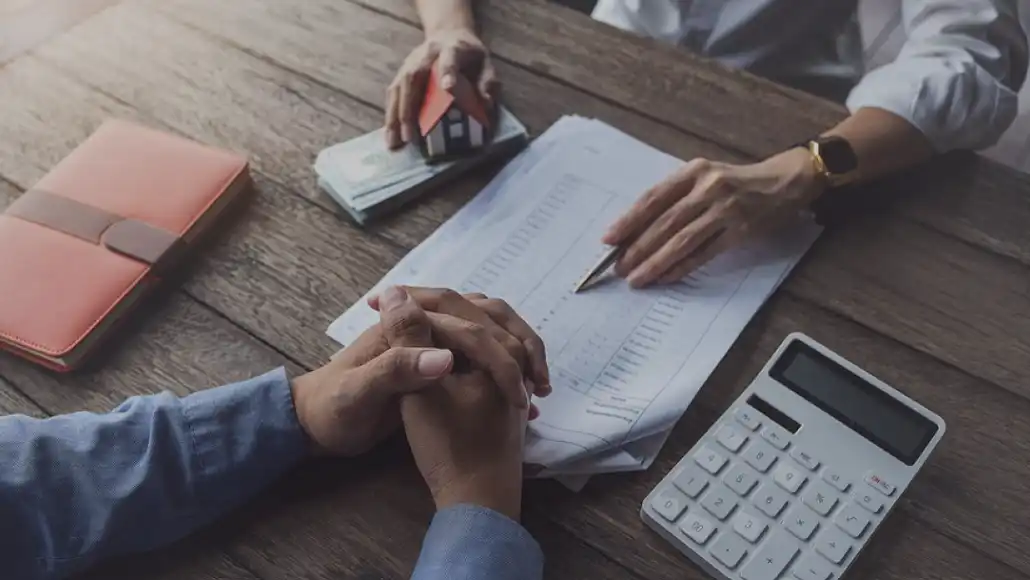 homeowner consulting with a tax advisor on selling a home with seller financing. photo is a piece of paper with an amortized schedule, and a calculator