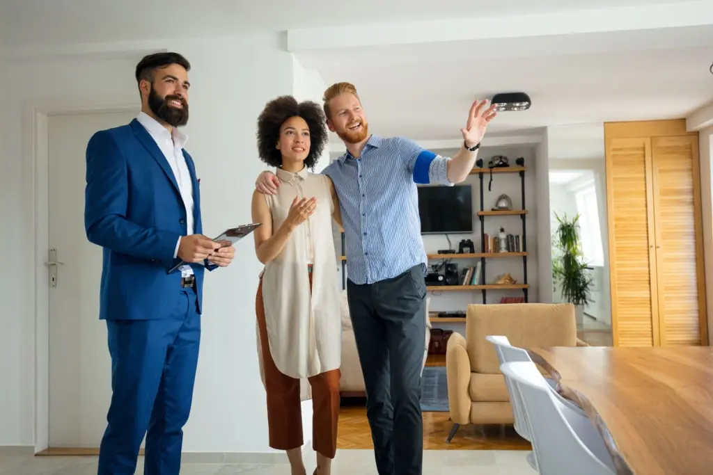 A potential buyer walking through a property, being shown by current tenants of the rental property. They have a smile on their faces as they are showing the property, a great sign of good tenants when selling a house with tenants in place.