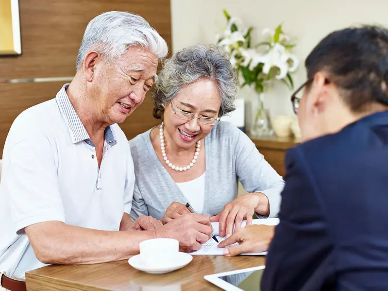 Elderly couple working with a loan advisor to refinance a reverse mortgage and adjust their home equity loan.