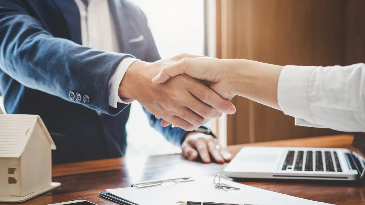 Homebuyer and homeowner shaking hands during a creative financing real estate agreement for an alternative home selling solution.