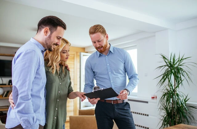 Homebuyers reviewing assumable mortgage documents with a real estate professional during a home purchase.
